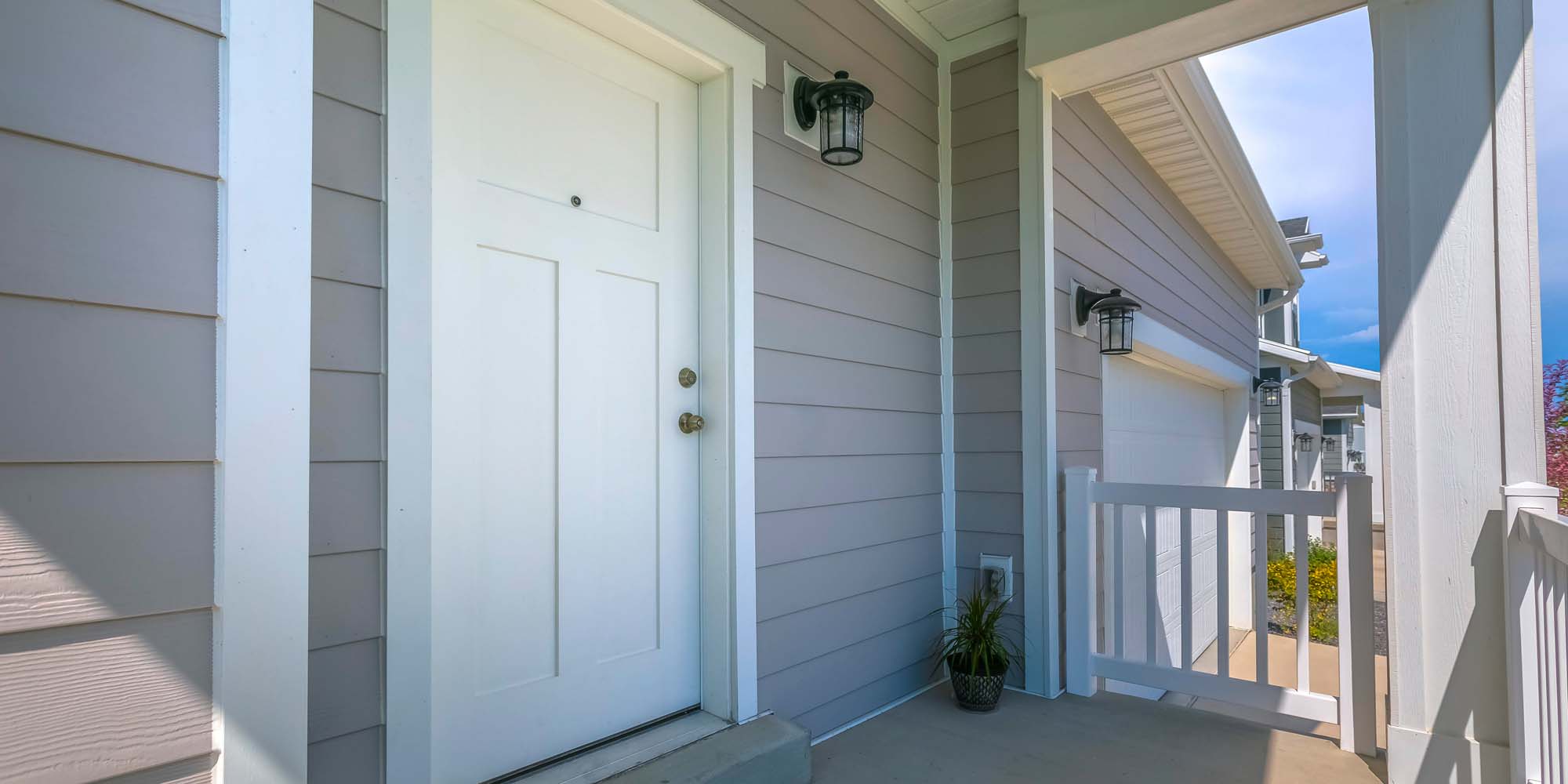 White front door and porch of home on a sunny day.
