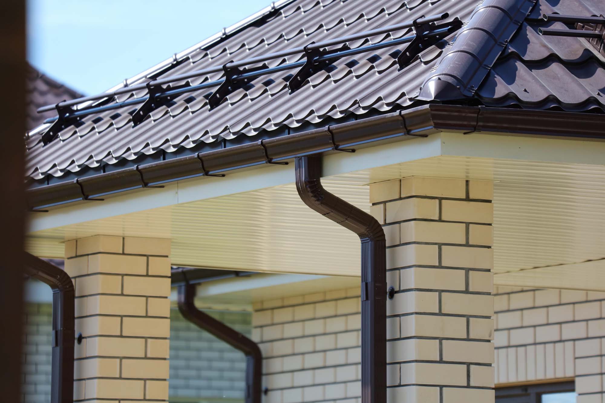 Brown metal gutter on the roof of the house